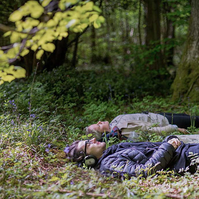 two people lying on a forest floor