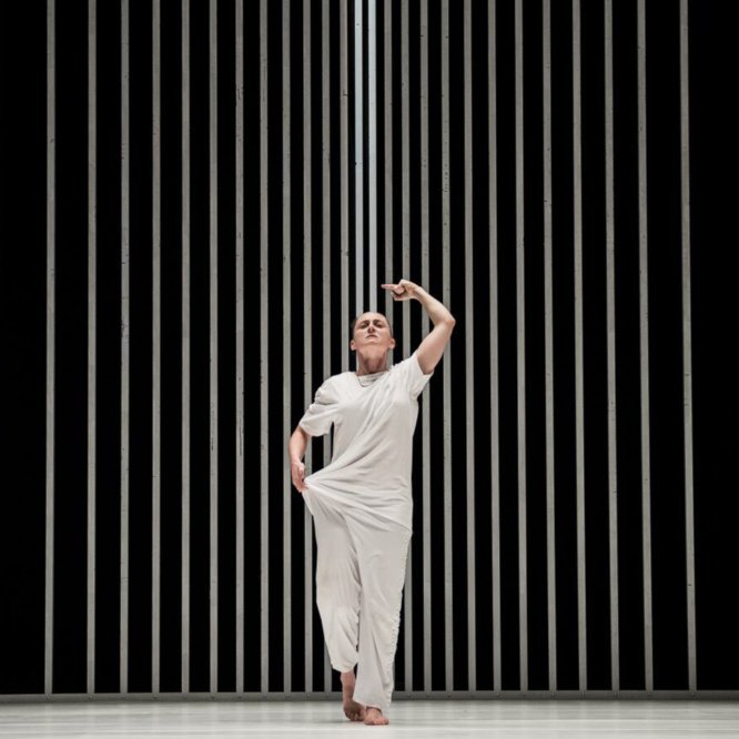 dancer in white with bars behind her